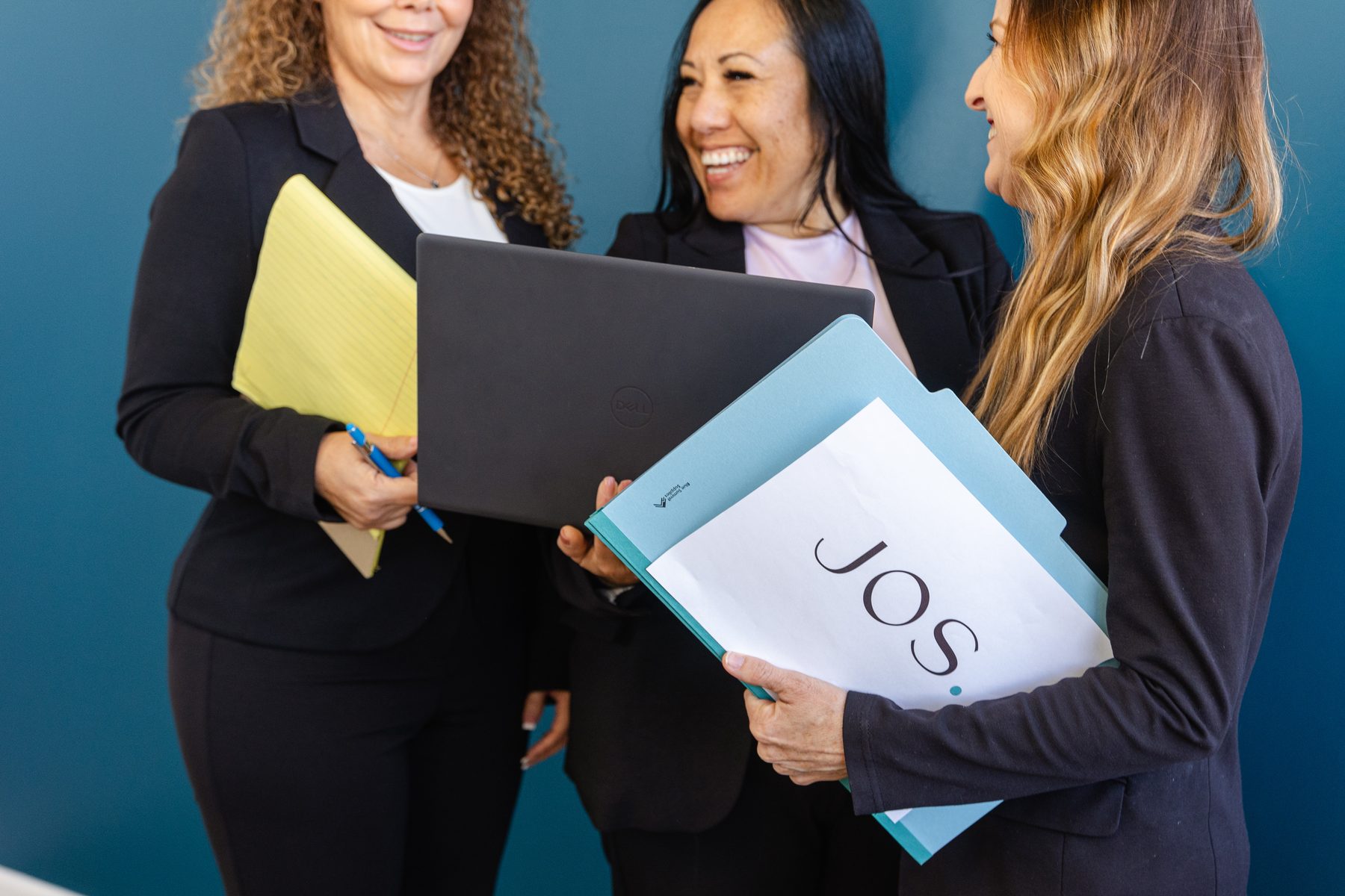Three women on the Jos Family Law team collaborating with laptops and branded folders